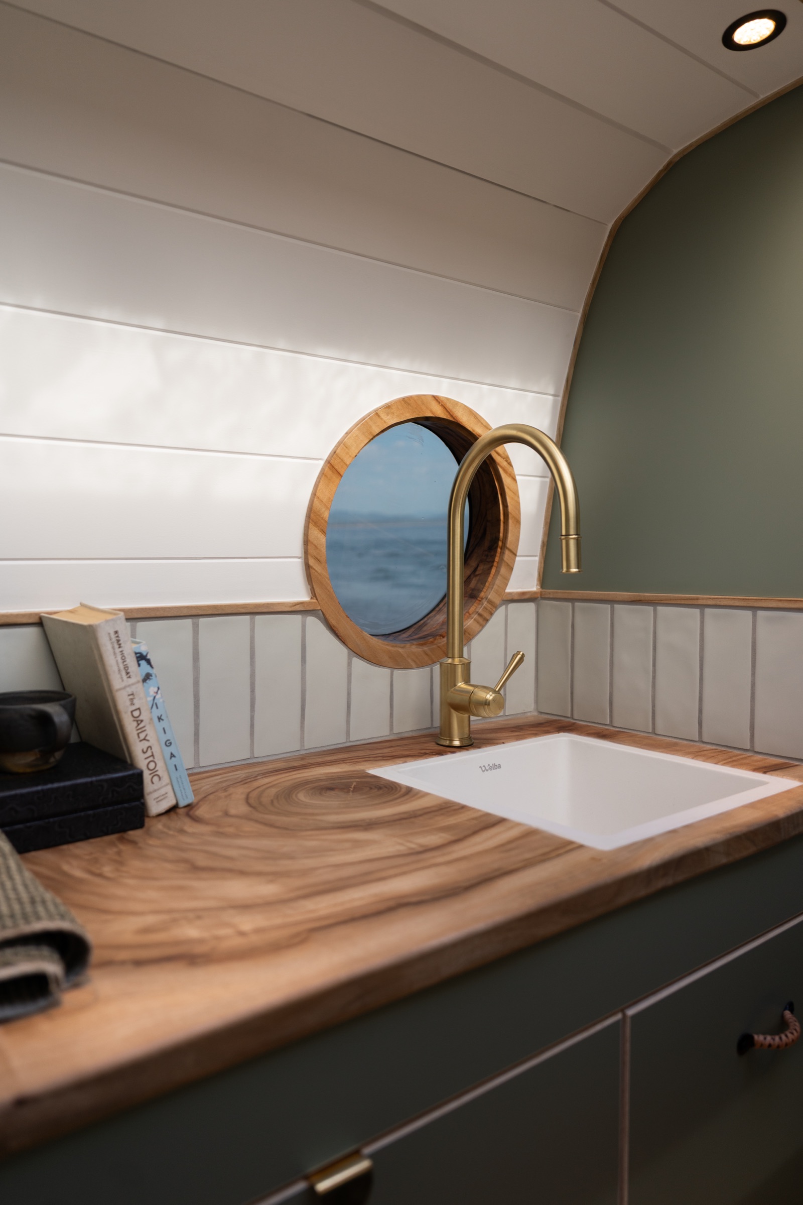 Brass tap and round mirror inside Sage